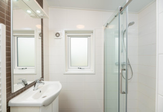 Moderne badeværelse på Sand Lodge Comfort i Veluwepark de Bosgraaf, Holland, med brusebad og håndvask.