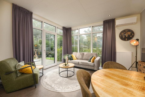 Sala moderna en Heather Lodge de Veluwepark de Bosgraaf, Países Bajos, con grandes ventanales y decoración.