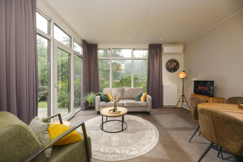 Stijlvolle woonkamer in Heather Lodge op Veluwepark de Bosgraaf, Nederland, met grote ramen en modern interieur.