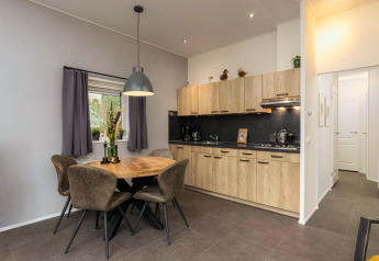 Moderne Küche und Essbereich in der Heather Lodge im Veluwepark de Bosgraaf, Niederlande, mit Holzoptik.