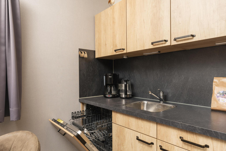 Cocina en Heather Lodge en Veluwepark de Bosgraaf, Países Bajos, con lavavajillas, fregadero y cafeteras.