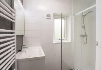 Bagno moderno con doccia in vetro, lavabo quadrato, piastrelle bianche e finestra presso Heather Lodge, Veluwe.