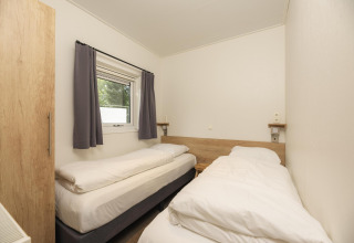 Dos camas individuales con sábanas blancas en una habitación de Heather Lodge en Veluwepark de Bosgraaf, Países Bajos.