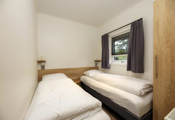 Kleines Schlafzimmer mit zwei Einzelbetten, Fenster mit Vorhängen und schlichter Einrichtung in Heather Lodge.