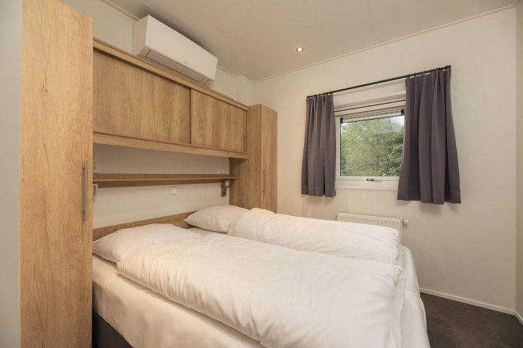 Dormitorio en Heather Lodge en Veluwepark de Bosgraaf, Países Bajos, con cama doble y ventana al exterior.