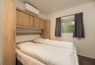 Dormitorio en Heather Lodge en Veluwepark de Bosgraaf, Países Bajos, con cama doble y ventana al exterior.