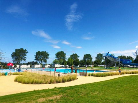 Buitenzwembad met glijbaan en vakantiehuisjes bij Kompas Camping Nieuwpoort, West-Vlaanderen, België.