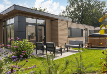 Außenansicht der Cannenburch Deluxe-Lodge mit stilvoller Terrasse, Garten und eigenem Whirlpool.