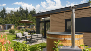 Luxe lodge met hottub en moderne terras bij Veluwepark de Bosgraaf in Nederland, omringd door natuur.