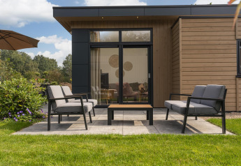 Terraza moderna del Cannenburch Deluxe lodge con asientos y jardín en Veluwepark de Bosgraaf, Países Bajos.