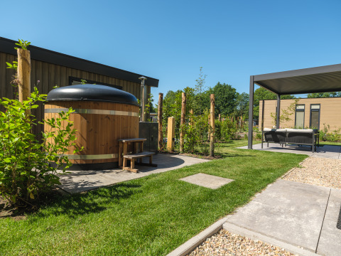 Udendørs område med spabad og overdækket lounge ved Loevestein Deluxe på Veluwepark de Bosgraaf, Holland.