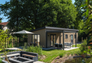Moderne lodge Loevestein Deluxe med boblebad i Veluwepark de Bosgraaf, omgivet af grønt område og udeplads.