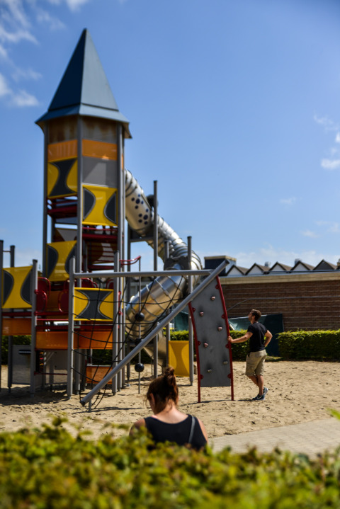 Speeltoren en glijbaan op Kompas Camping Nieuwpoort in West-Vlaanderen, België, met mensen buiten.