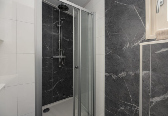 Ducha moderna con puertas de vidrio y baldosas oscuras en Loevestein Deluxe, Veluwepark de Bosgraaf, Países Bajos.