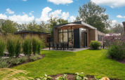 Lodge moderne avec terrasse, mobilier extérieur et parasol dans un jardin à Veluwepark de Bosgraaf, Pays-Bas.