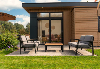Terraza moderna con asientos al aire libre frente a un lodge en Cannenburch con jacuzzi en Veluwepark de Bosgraaf.