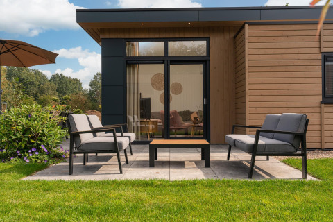 Moderne Terrasse mit Gartenmöbeln vor einer Lodge in Cannenburch mit Whirlpool im Veluwepark de Bosgraaf, Niederlande.