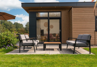 Terraza moderna con asientos al aire libre frente a un lodge en Cannenburch con jacuzzi en Veluwepark de Bosgraaf.