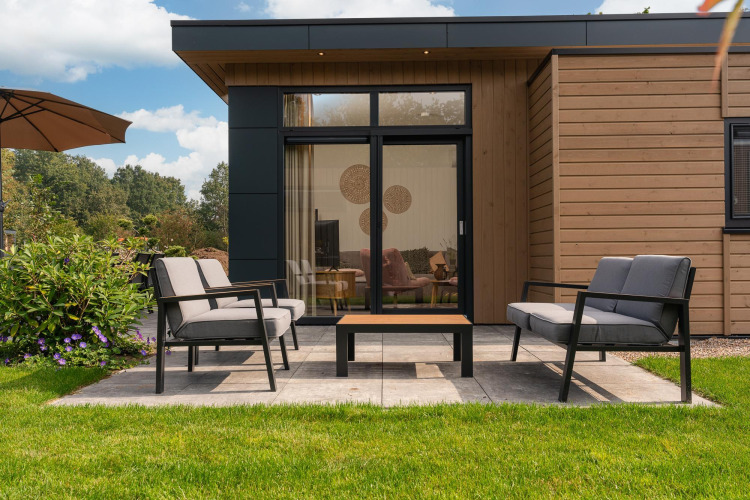 Moderne Terrasse mit Gartenmöbeln vor einer Lodge in Cannenburch mit Whirlpool im Veluwepark de Bosgraaf, Niederlande.