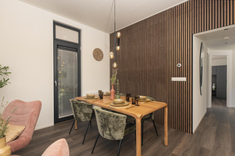 Comedor moderno en la cabaña Cannenburch con pared de listones, mesa puesta y decoración elegante en Holanda.