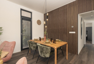 Comedor moderno en la cabaña Cannenburch con pared de listones, mesa puesta y decoración elegante en Holanda.