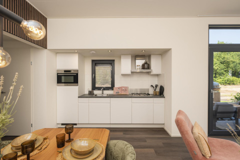 Cucina moderna e zona pranzo al Lodge Cannenburch con vasca idromassaggio a Veluwepark de Bosgraaf, Paesi Bassi.