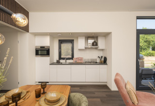 Cucina moderna e zona pranzo al Lodge Cannenburch con vasca idromassaggio a Veluwepark de Bosgraaf, Paesi Bassi.