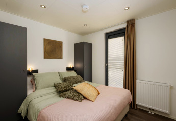 Dormitorio de la cabaña Cannenburch en Veluwepark de Bosgraaf, Países Bajos, con decoración moderna y acceso a jacuzzi.