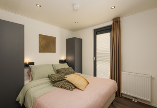 Camera da letto della lodge Cannenburch al Veluwepark de Bosgraaf, Paesi Bassi, con arredo moderno e accesso alla vasca idromassaggio.