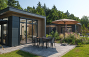Lodge moderno con patio e ombrellone al Veluwepark de Bosgraaf, immerso nel verde e nella natura.
