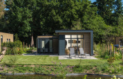Lodge Essenburgh Comfort moderne avec terrasse et transats dans un jardin verdoyant au Veluwepark de Bosgraaf, Pays-Bas.