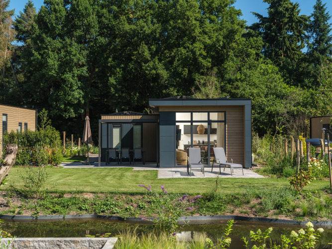 Moderne Essenburgh Comfort lodge met terras, ligstoelen en tuin bij Veluwepark de Bosgraaf, Nederland.