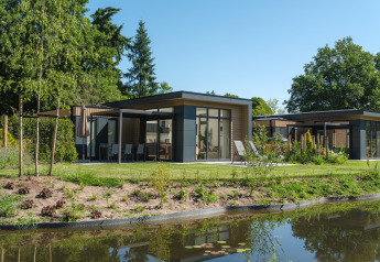 Modern Essenburgh Comfort lodge with hot tub at Veluwepark de Bosgraaf in the Netherlands, by a pond.
