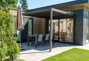 Moderne Lodge mit überdachter Terrasse und Gartenmöbeln am Veluwepark de Bosgraaf in den Niederlanden.