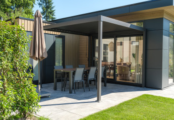 Moderne lodge met overdekt terras en tuinset bij Veluwepark de Bosgraaf in Nederland.