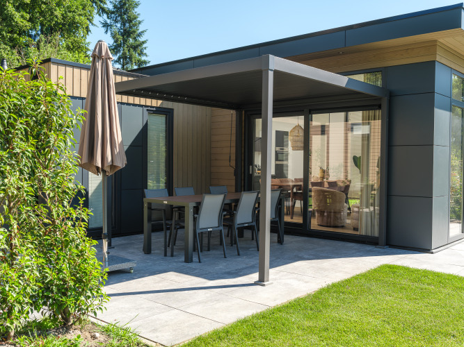 Moderne lodge met overdekt terras en tuinset bij Veluwepark de Bosgraaf in Nederland.
