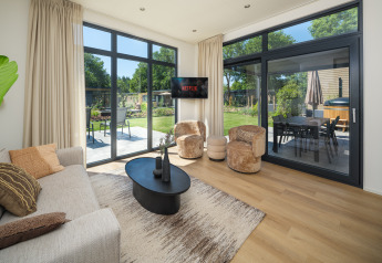 Soggiorno moderno alla lodge Essenburgh Comfort con vista giardino e vasca idromassaggio a Veluwepark de Bosgraaf.