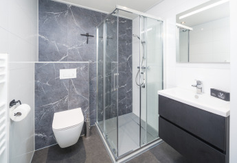 Moderne badeværelse med bruseniche, væghængt toilet og håndvask på Essenburgh Comfort i Veluwepark de Bosgraaf.