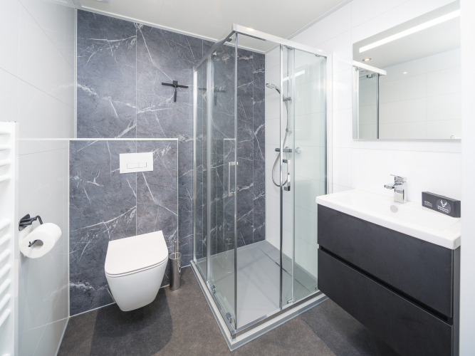 Modernes Badezimmer mit Dusche, Wandtoilette und Waschbecken im Essenburgh Comfort in Veluwepark de Bosgraaf.