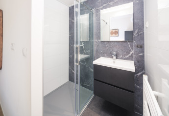 Modern bathroom at Essenburgh Comfort, Veluwepark de Bosgraaf, featuring shower and sink area.