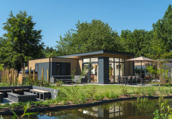 Lodge Essenburgh Deluxe moderne avec jacuzzi, espace repas extérieur, terrasse et étang dans la nature.