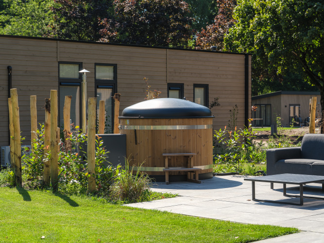 Außenaufnahme eines Essenburgh Deluxe-Lodge mit Whirlpool im Veluwepark de Bosgraaf in den Niederlanden.