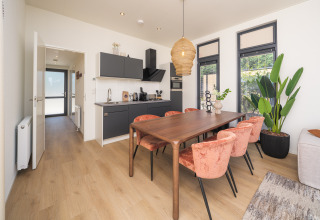 Moderne lodge med spisebord, køkken og store vinduer, Essenburgh Deluxe på Veluwepark de Bosgraaf, Holland.