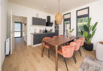 Modern lodge interior with kitchen, dining area, and large windows at Essenburgh Deluxe, Veluwepark de Bosgraaf, NL.
