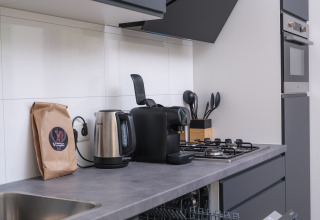 Kitchenette moderne avec bouilloire, machine à café et cuisinière à Essenburgh Deluxe Lodge, Veluwepark de Bosgraaf.