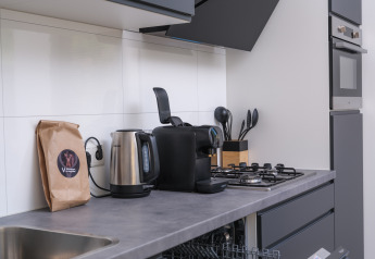 Kitchenette moderne avec bouilloire, machine à café et cuisinière à Essenburgh Deluxe Lodge, Veluwepark de Bosgraaf.