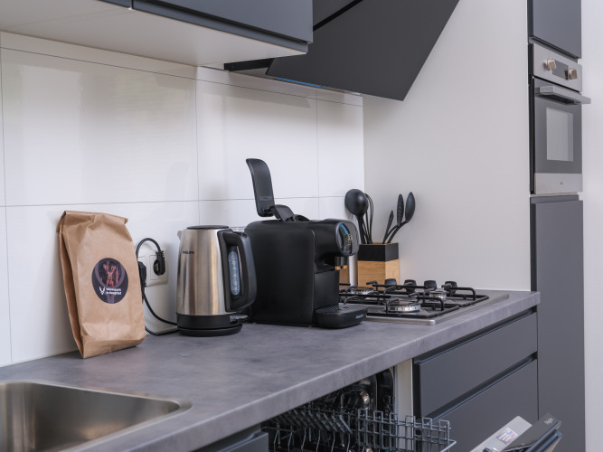 Moderne Küchenzeile mit Wasserkocher, Kaffeemaschine und Herd in einer Essenburgh Deluxe-Lodge in Veluwepark de Bosgraaf.
