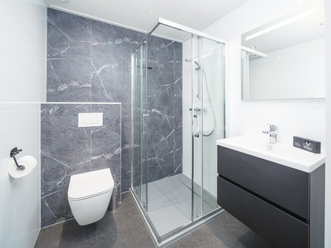 Modernes Badezimmer im Essenburgh Deluxe mit eleganter Dusche und Waschbecken im Veluwepark de Bosgraaf.