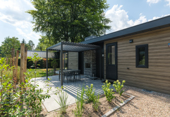Lodge moderne au Veluwepark de Bosgraaf, Pays-Bas, avec terrasse, jardin et pergola sous ciel bleu.