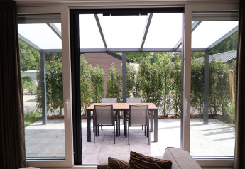 Vista desde la sala hacia una terraza con mesa y sillas en Rosendael Comfort met hottub, Veluwepark de Bosgraaf, Países Bajos.